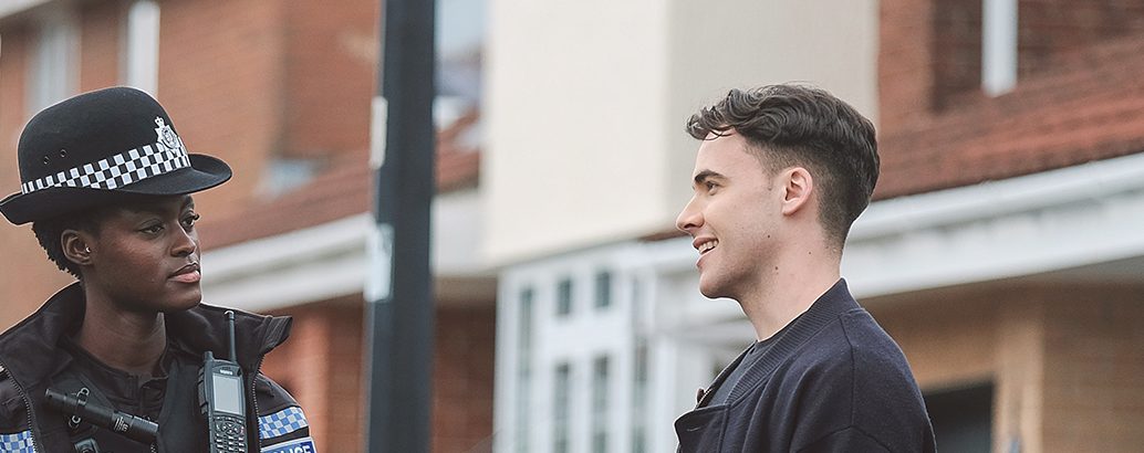 a person talking to a uniformed police officer in a suburban street environment