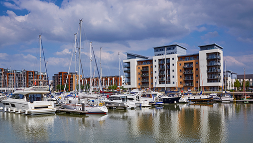 a marina with a number of ships and high rise flats in the background