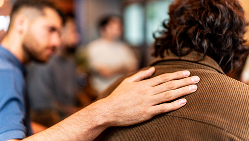 an adult comforts a younger person in a support group setting