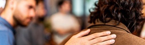 an adult comforts a younger person in a support group setting